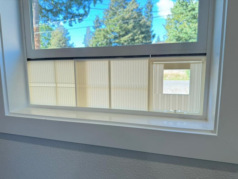 Close-up of the adjustable cat door insert fitted under a raised window sash